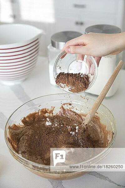 sifting cocoa powder into mixing bowl to make chocolate frosting