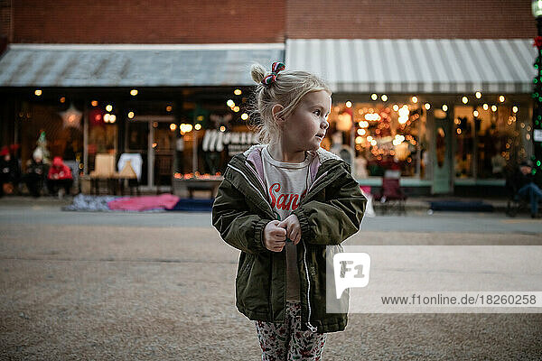 Young girl standing in front of downtown Christmas shops