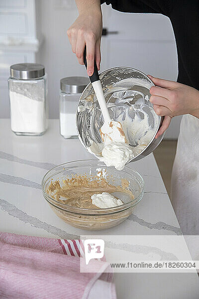 female hands using spatula to take make whipped cream out of bowl