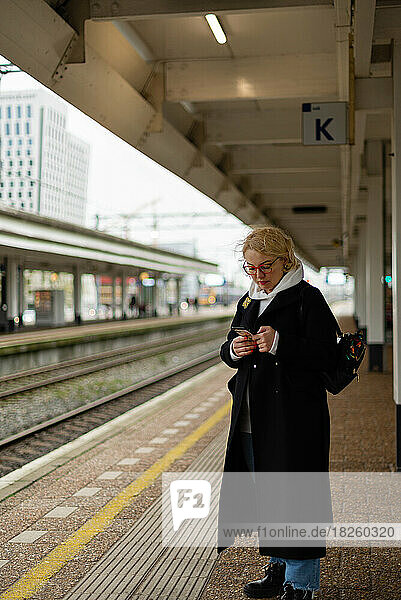 Woman on the rialway station platform with the phone in hands