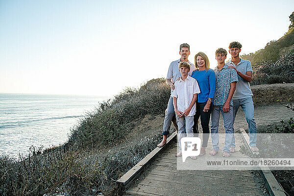 Happy Family Stand On Wooden Path Next To The Ocean