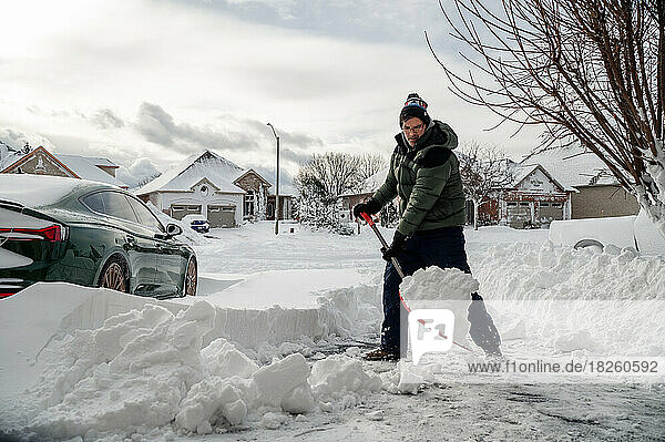 Man shoveling snow off of his driveway after a winter storm.