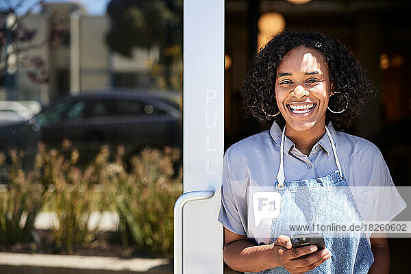Portrait of happy female entrepreneur holding smart phone