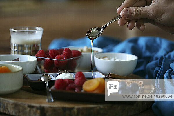 honey being drizzled onto fruit charcuterie platter