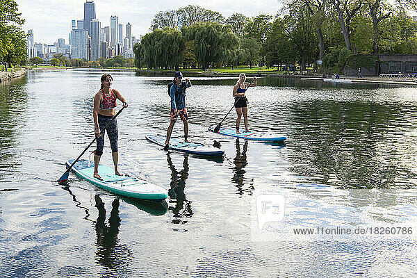 Male and female friends paddleboarding in river