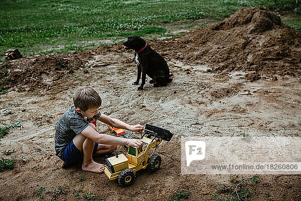 Boy playing tractors in dirt in yard at home
