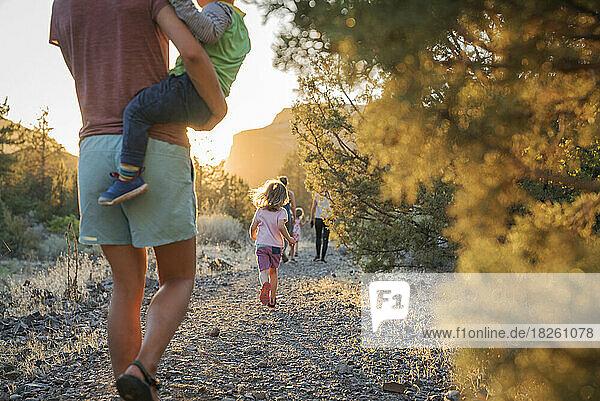 A mom walks with kids down a trail at sunset