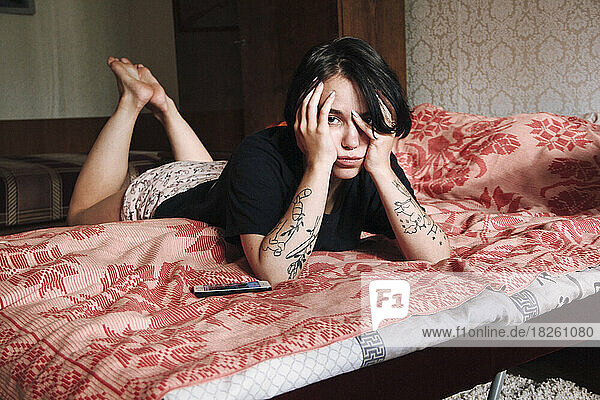 young hipster woman lying on bed on stomach