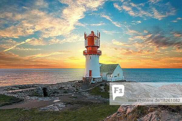 lighthouse surrounded by rocks at sunset