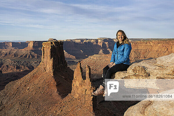Portrait of cheerful woman sitting on rock in desert