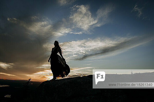 woman in long dress flowing hair at silhouetted at sunset