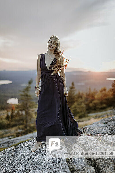 beautiful blonde woman barefoot in long dress with tattoo at sunset