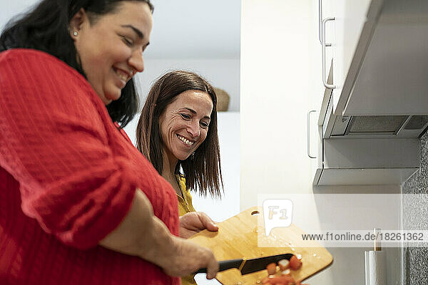Two diverse friends preparing lunch in the kitchen with her friend.