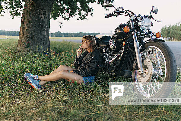 Young woman with a cigarette sitting near a motorcycle