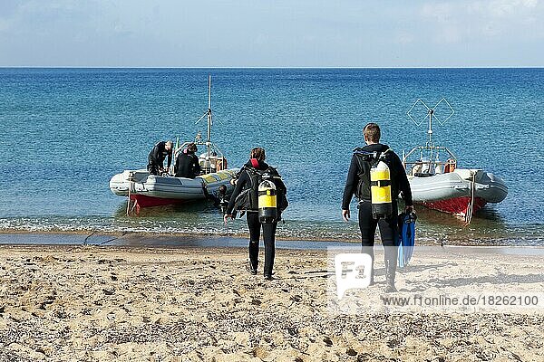 Taucher Sporttaucher laufen mit Tauchausrüstung Tauchgeräte Pressluftflaschen über Strand Sandstrand von Mittelmeer zu Schlauchboot  Italien  Europa