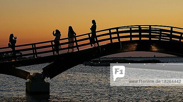 Abenddämmerung  Sonnenuntergang  Holzbrücke  Fußgängerbrücke über Kanal  Schattenriss  Fußgänger  vier junge Frauen machen Selfies  Lefkada-Stadt  Hauptstadt  Insel Lefkada  Lefkas  Ionische Inseln  Griechenland  Europa