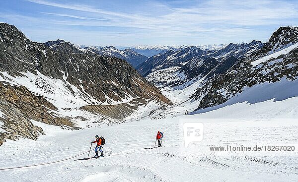 Two ski tourers walking on the rope on the glacier  ascent on the Berglasferner  view of the Berglastal valley and the summit Berglasspitze  Stubai Alps  Tyrol  Austria  Europe