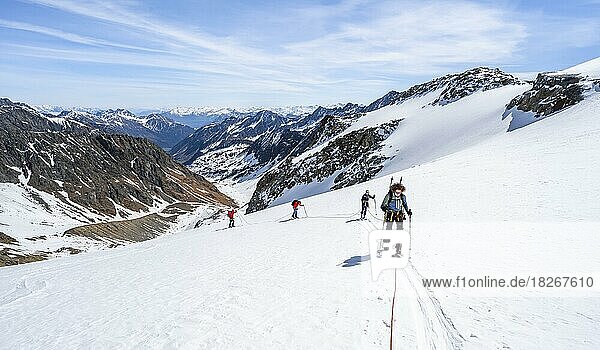 Ski tourers walking on the rope on the glacier  ascent on Berglasferner  view of the Berglastal valley and mountain panorama  Stubai Alps  Tyrol  Austria  Europe