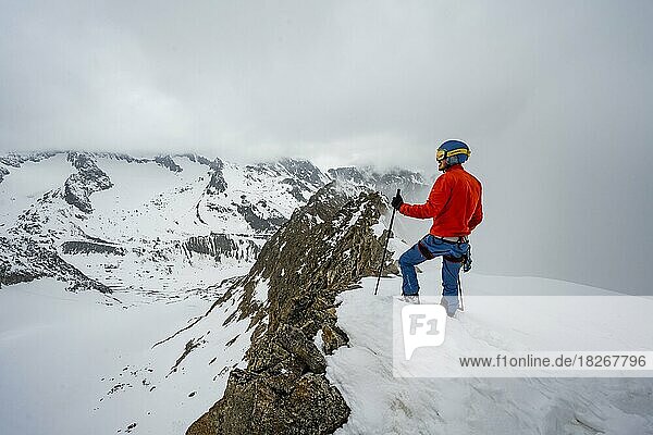 Ski tourers on rocky ridge with snow  Obere Kräulscharte  view to Inner Sommerwand  Sommerwandferner glacier  cloudy mountains  Stubai Alps  Tyrol  Austria  Europe