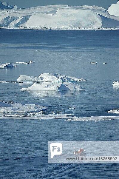 Boat in front of huge icebergs and drift ice  fishing  winter  evening mood  Disko Bay  Ilulissat  Arctic  Greenland  Denmark  North America