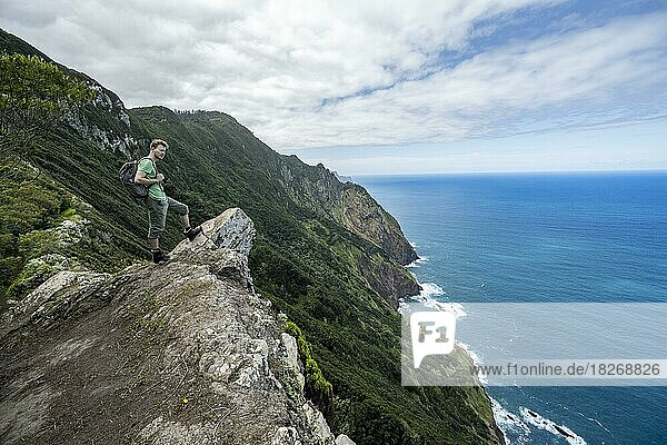 Wanderer steht an einem Grat  Ausblick auf steile felsige Küste und Meer  Küstenlandschaft  Wanderweg Vereda do Larano  Madeira  Portugal  Europa