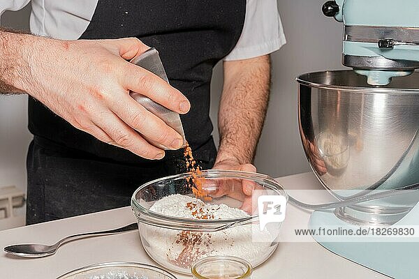 A man baker cooking a red velvet cake at home  preparing the cake by adding cocoa powder with flour and yeast in the food processor  work at home