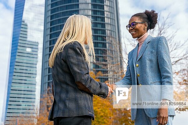 Multiethnische Geschäftsfrauen und Führungskräfte mittleren Alters  die sich vor ihren Büros per Handschlag begrüßen