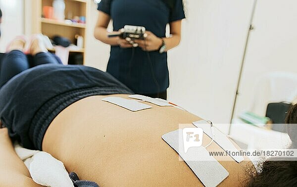 Elektrostimulation eines Patienten durch einen Physiotherapeuten  Elektrodenbehandlung eines liegenden Patienten  Elektrostimulation eines liegenden Patienten durch einen professionellen Physiotherapeuten. Therapie des unteren Rückens mit Elektrodenpads