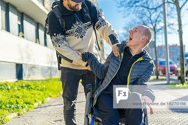 Disabled person in a wheelchair laughing with a friend in a chair on the street in winter