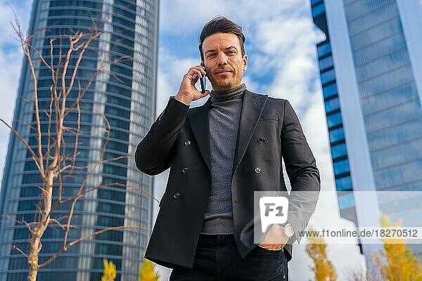 Corporate Porträt der kaukasischen Geschäftsmann am Telefon neben Wolkenkratzer Büro sprechen