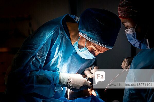 Zahnklinik  Zahnarzt und Assistentin führen eine orale Operation bei schwachem Licht durch