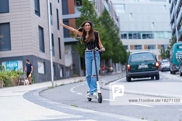 Eine junge brünette Frau  die sich mit einem Elektroroller in der Stadt bewegt und Spaß hat  entlang des Radwegs