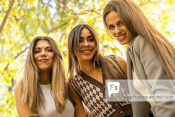 Portrait of carefree women friends smiling in a park in autumn  trendy autumn lifestyle
