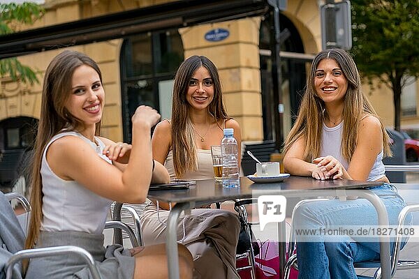 Porträt von jungen Freundinnen  die an einem Nachmittag auf der Terrasse einer Cafeteria etwas trinken