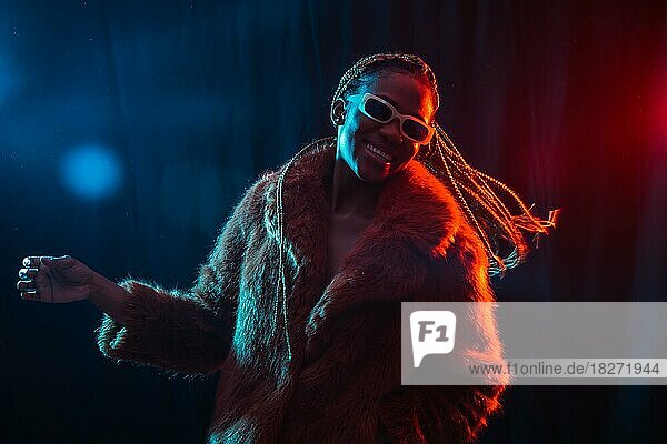 Schwarze ethnische Frau mit Zöpfen mit blauen und roten Lichtern  Modell mit Spaß und Tanz