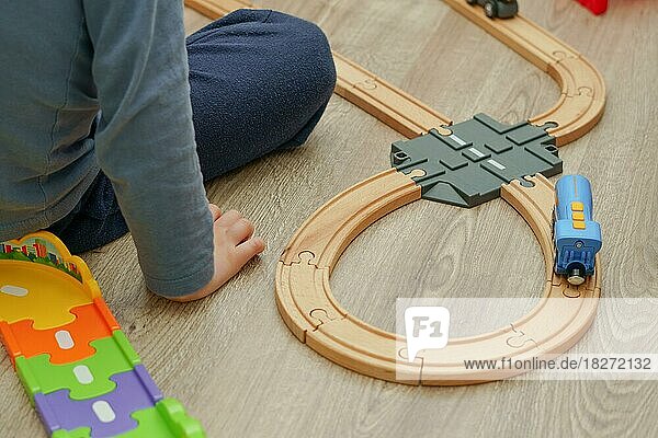kleiner Junge spielt in seinem Zimmer mit einer blauen Eisenbahn