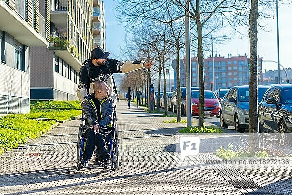 Eine behinderte Person geht mit einem Freund im Rollstuhl auf der Straße spazieren