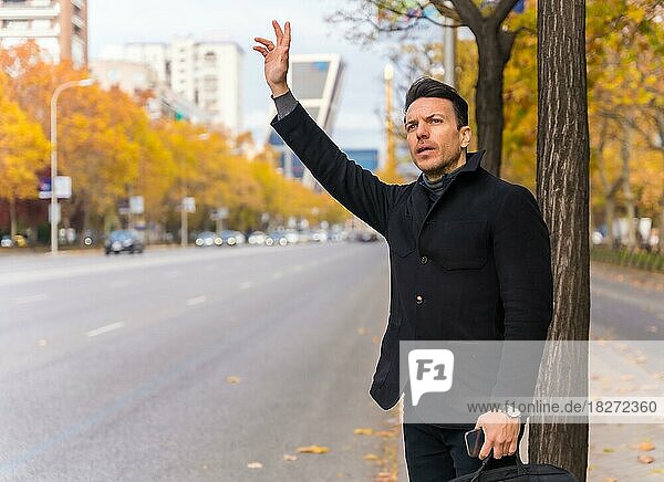 Kaukasischer Geschäftsmann mittleren Alters  der ein Taxi ruft und seine Hand hebt  um zur Arbeit zu fahren