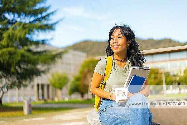 Asian girl on campus  student with blocks in hand and backpack  smiling at university