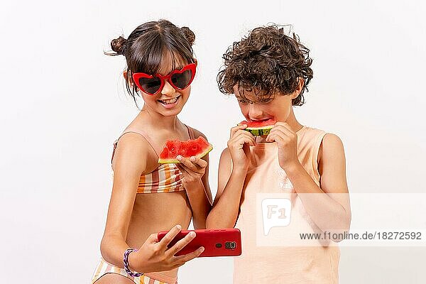 Kinder genießen den Sommer  essen eine Wassermelone und machen ein Selfie mit dem Handy. Weißer Hintergrund