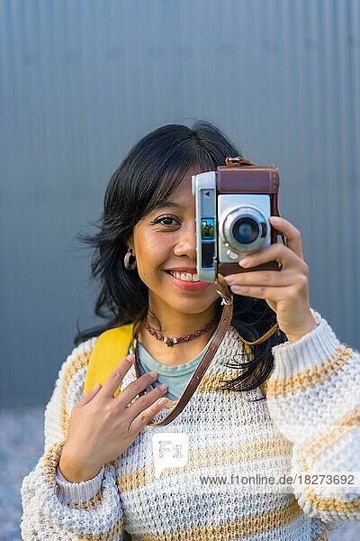 Porträt einer jungen asiatischen Frau  die mit einer alten Fotokamera fotografiert  Urlaubskonzept  die ihr Auge bedeckt