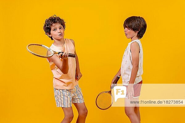 Zwei Kinder spielen Tennis und haben Spaß im Sommer  gelber Hintergrund