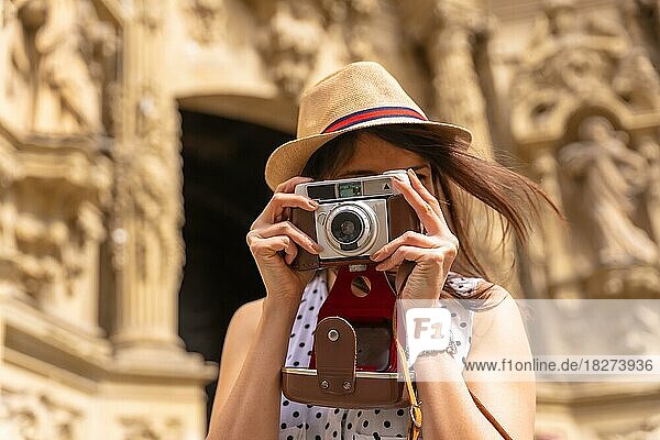 Hübsche Touristin mit Hut  die mit einer Fotokamera eine Kirche besucht und den Frühling oder Sommerurlaub genießt  Konzept einer weiblichen Reisenden und Erstellerin digitaler Inhalte
