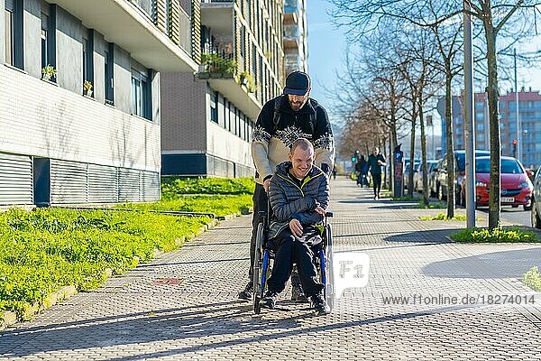 Behinderte Person  die mit einem Freund im Rollstuhl auf der Straße spazieren geht