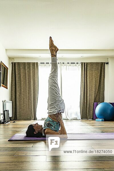 Seitenansicht einer Yogapraktizierenden  die die Schulterstand-Pose einnimmt. Yoga-Studio