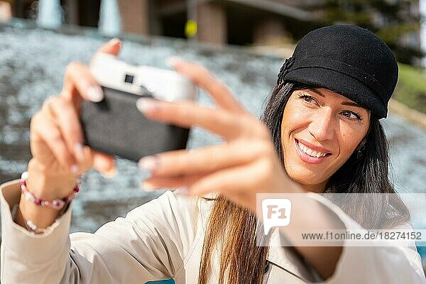 Lächelnde Touristin  die in ihrem Sommerurlaub in der Stadt ein Selfie mit der Fotokamera macht