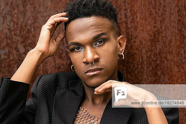 Portrait of a model man of black ethnicity in a fashion pose on a brown metallic background