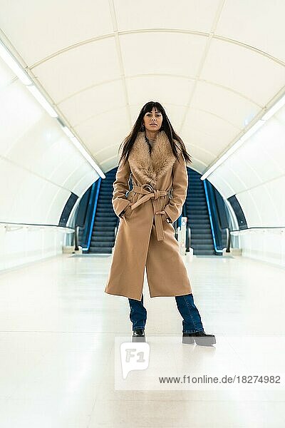 Brünettes Mädchen steigt im Winter mit einer Jacke in die U-Bahn ein. Hübsche Kaukasierin geht durch den Tunnel