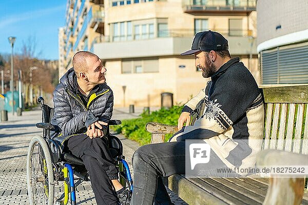 Behinderte Person im Rollstuhl mit einem Freund  der sich amüsiert und unterhält