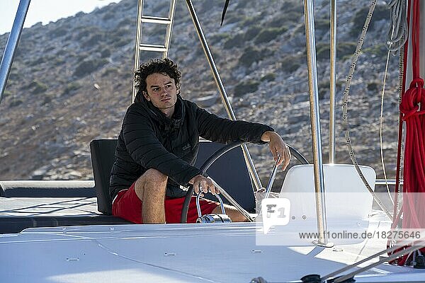 Man steering a sailing catamaran while sailing  South Aegean  Greece  Europe